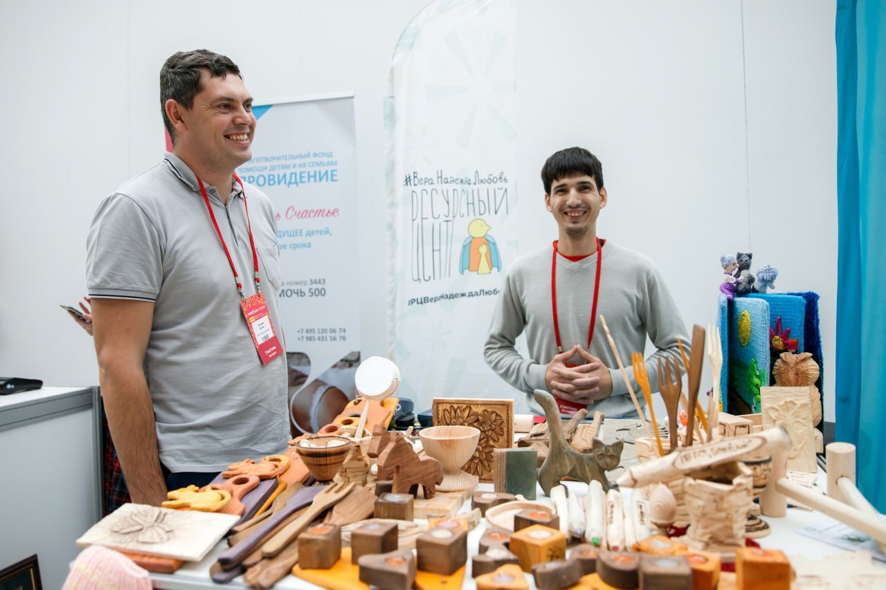 Ярмарка изделий из дерева, два человека за прилавком улыбаются